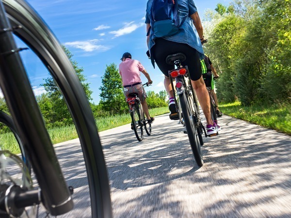Kikkerperspectief van fietsende mensen op een asfeltweg in de natuur